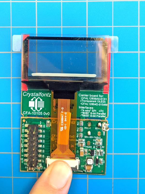 Display inserted into ZIF connector on breakout board with finger to close ZIF connector