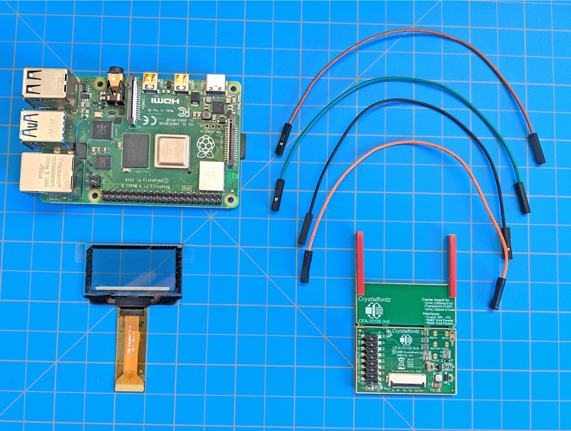 A raspberry pi, transparent OLED display, CFA10105 OLED breakout board, and four jumper wires laid out