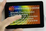 800x480 Sunlight Readable TFT Display with overhanging capacitive touchscreen. Front view, with hand to show size and perspective.