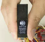 64x128 in-cell touchscreen graphic OLED display with a breakout board. shown in hand to show size and perspective.